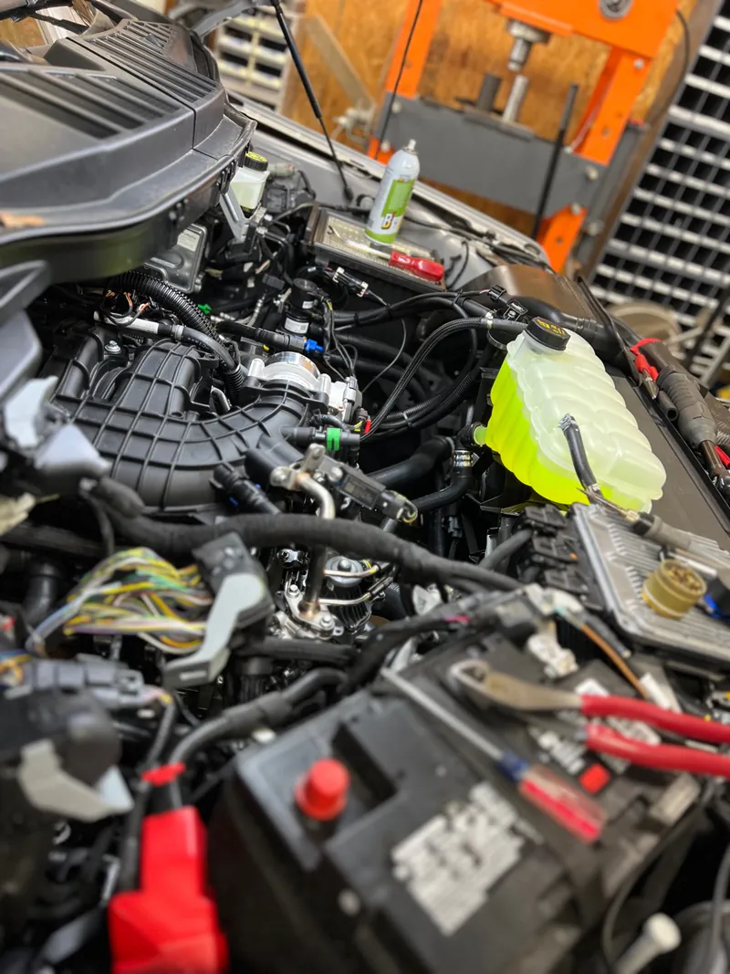 Propane fleet-conversion hardware routed inside a pickup engine bay at McElroy Auto Repair