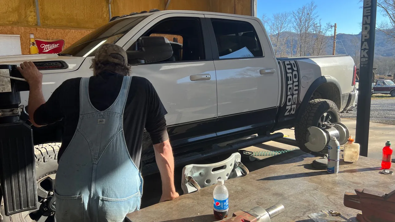 A technician working beside a pickup in the McElroy Auto Repair service bay