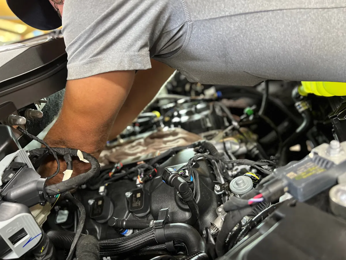 A technician working in a vehicle engine bay at McElroy Auto Repair