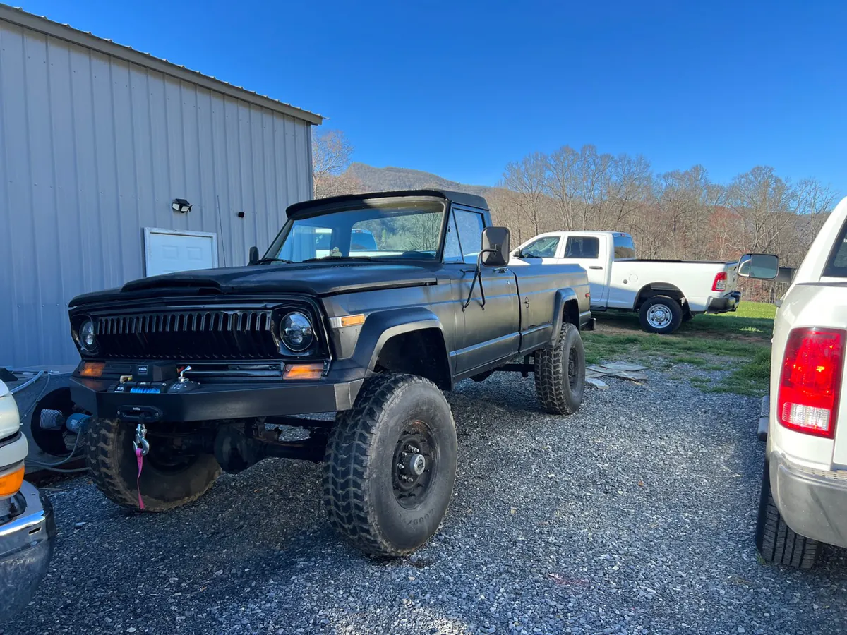 A modified vintage pickup parked in the gravel yard beside McElroy Auto Repair